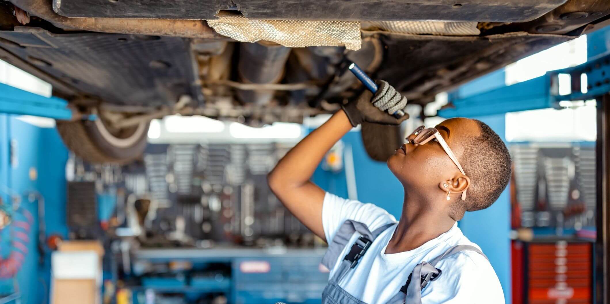 Young mechanic looks underneath a car