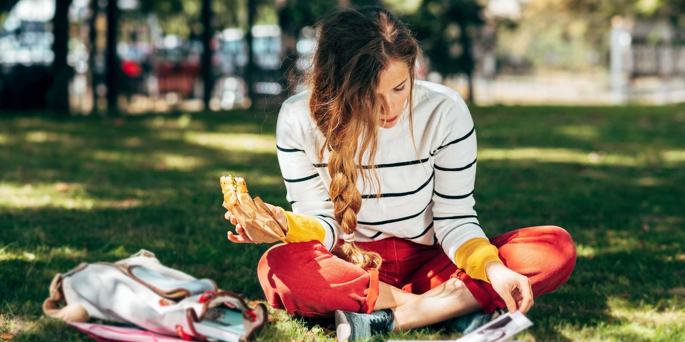 College student sits in grass to study and eat lunch