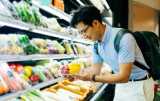 Asian young man shopping for fresh groceries in supermarket.