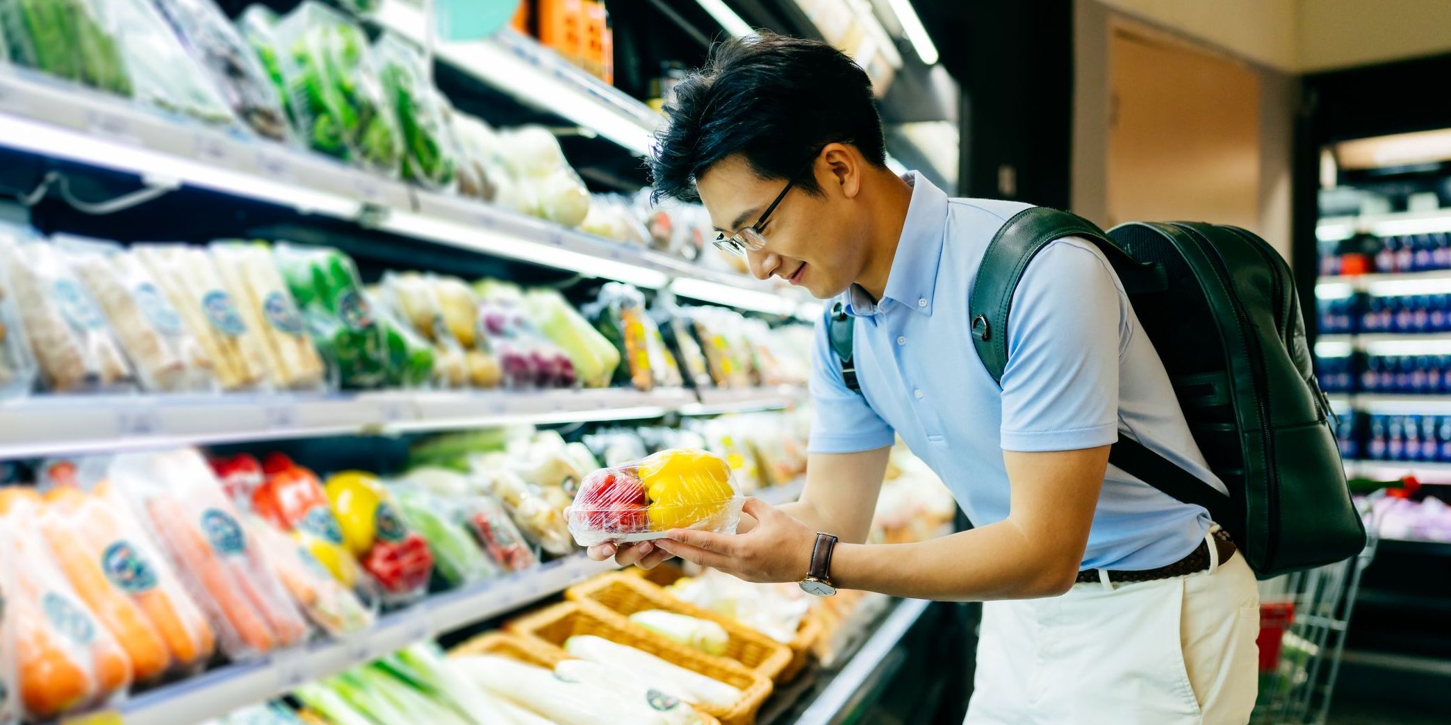 Asian young man shopping for fresh groceries in supermarket.