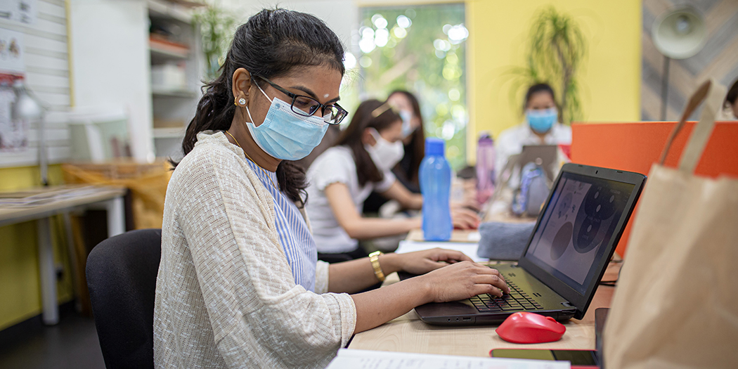 A student in a mask works at her computer