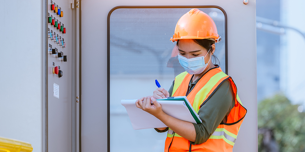 A construction work in a mask checks her clipboard