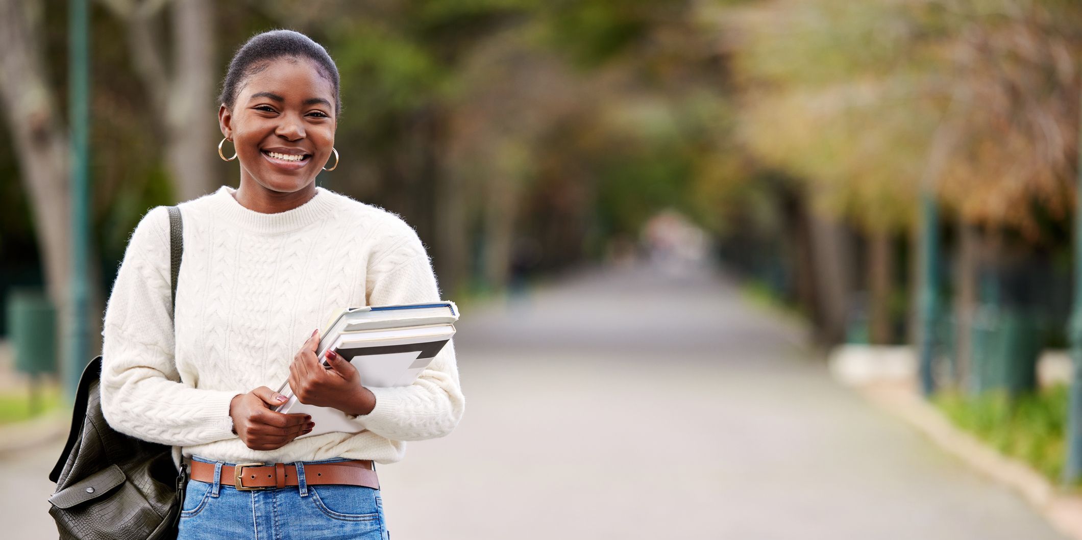 Shot of a young woman carrying her schoolbooks outside at college