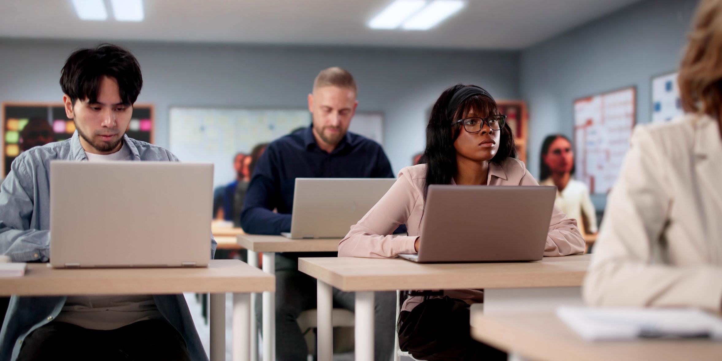 Students in a college classroom with laptops at their desks.