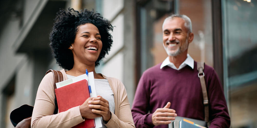 A student and professor walk, smiling