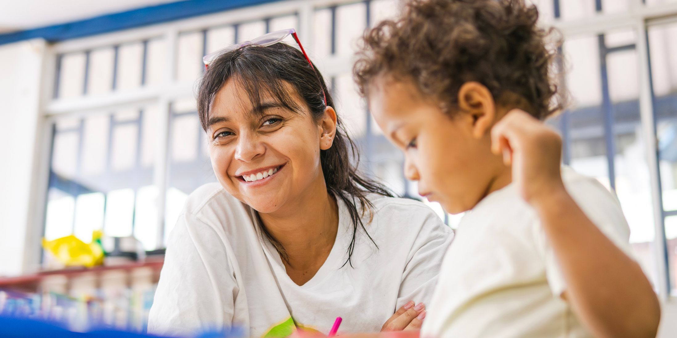 Happy teacher smiling with a child in preschool