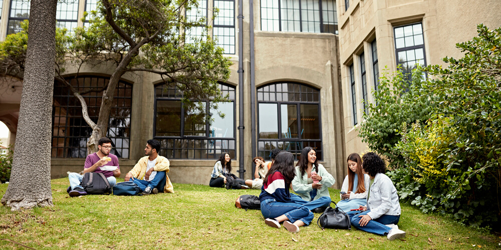 Image of students sitting on a college lawn.