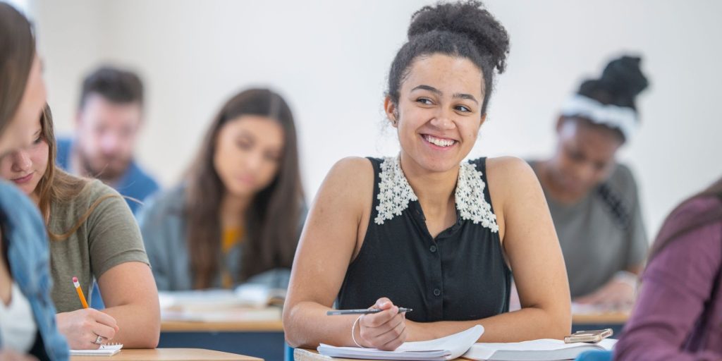 Student smiles while taking notes in class