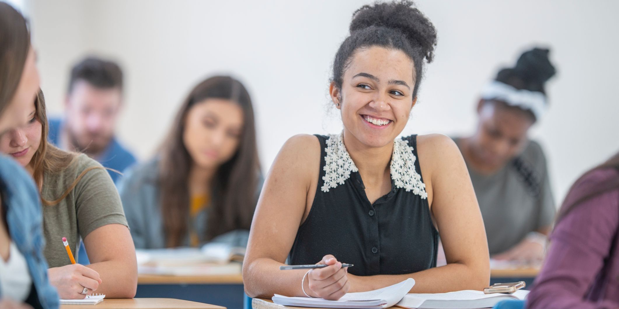 Student smiles while taking notes in class